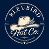 A circular vintage-style logo for Bleubird Hat Co. on a dark navy background, featuring an illustrated cream cowboy hat with a feather and the text 'BLEUBIRD Hat Co.
