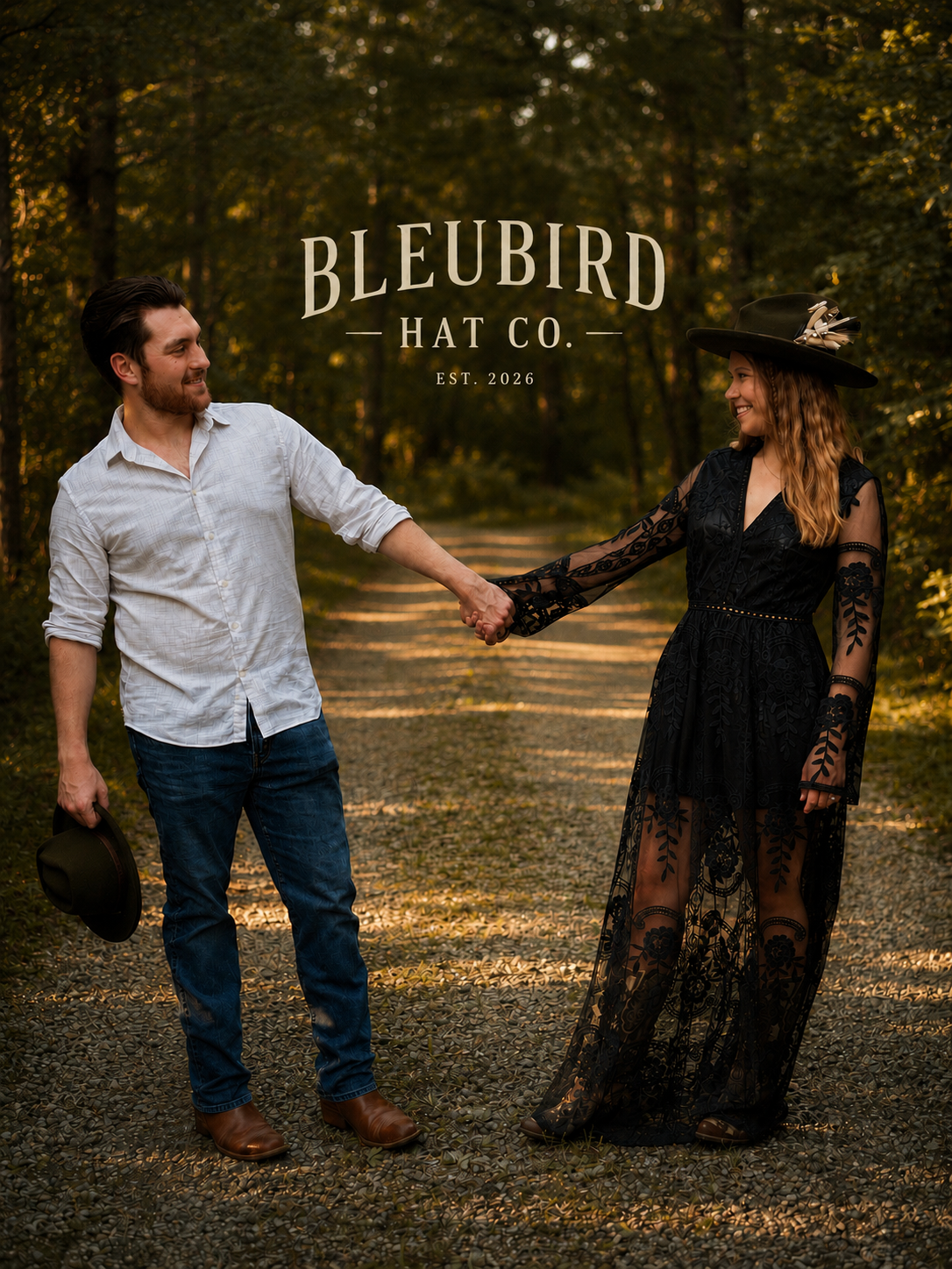 A man and woman holding hands on a gravel path in a wooded outdoor setting, with the text 'BLEUBIRD HAT CO. EST. 2026