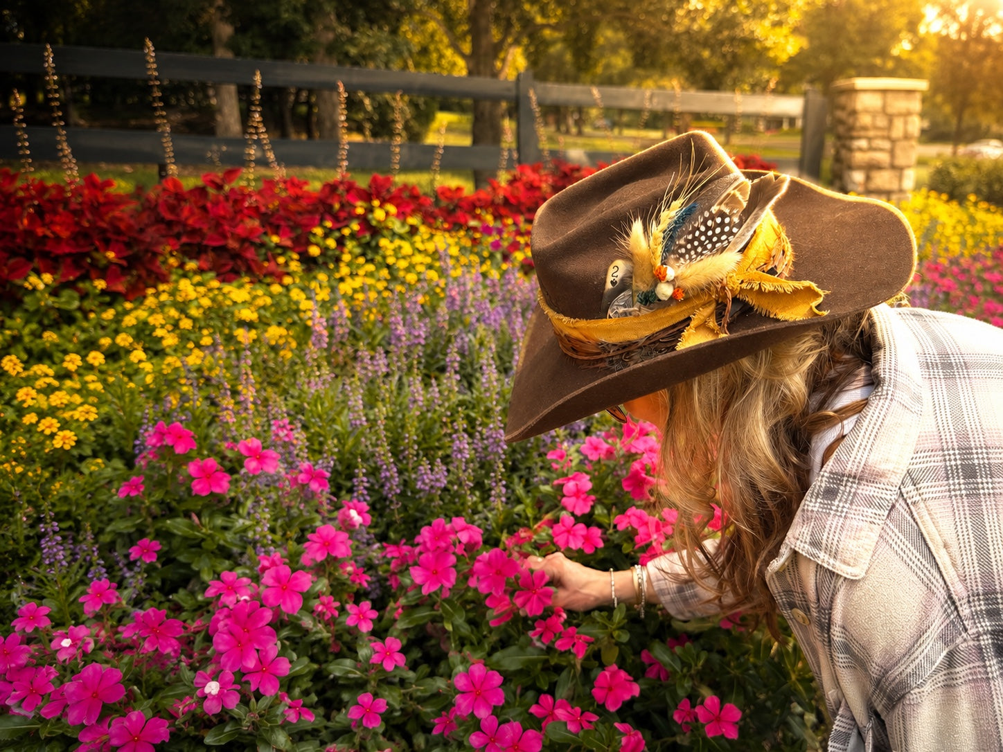 girl in front of flowers, sun hitting Brown hat